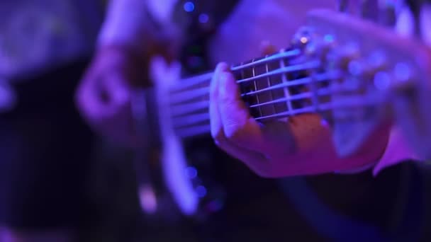 Closeup headstock bass. Bassist hand playing the bass guitar in concert/party/wedding. Performance under lights