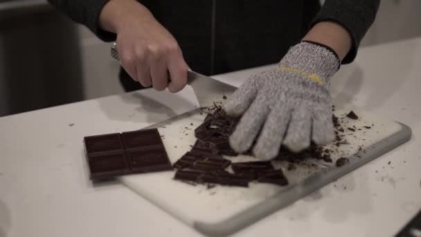 若い女の子はダークチョコレートを切り取りますそれを溶かす前に億万長者のショートブレッドクッキー安全手袋を身に着けている間 — ストック動画