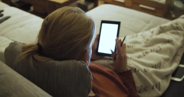 Young Woman Lies Sofa Cozy Blanket Uses Her Tablet Stylus — Stock Video