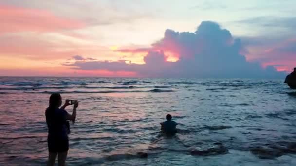 海の上の雲の後ろの美しい夕日に向かって人々を通過ドローンショット — ストック動画