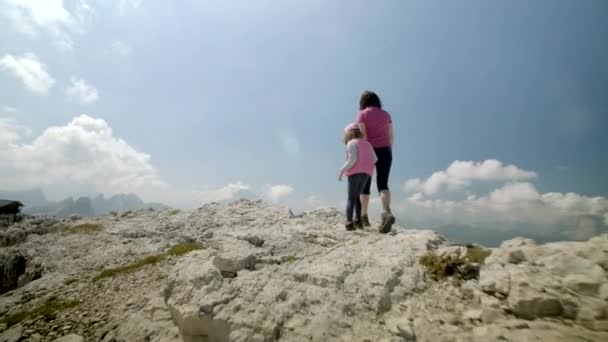 在一个阳光灿烂的夏日 妈妈和小女儿手牵着手 走向山边 欣赏着令人叹为观止的岩石山 — 图库视频影像