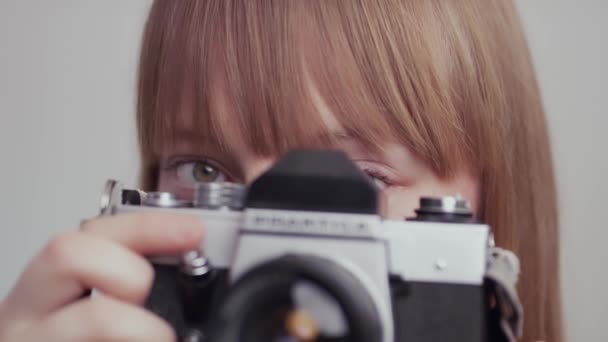 Fényképész a kamera mögött fotózkodik, egy nő fényképez, fehér háttér