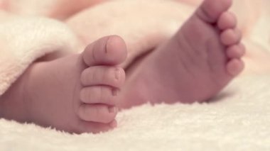 Yeni doğmuş güzel bebek yatakta uzanıyor ve ellerini ve ayaklarını gösteriyor, annesi bebeğe sarkıyor ve onu sıcacık bir örtüyle örtüyor, 4k 60p Apple Prores422, harici atomlar kaydedicisiyle.