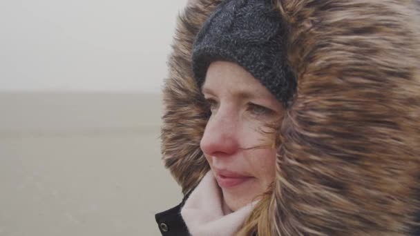年轻女子站在贫瘠的土地上的风中 用毛皮帽挡住寒冷的寒冷 慢动作 — 图库视频影像