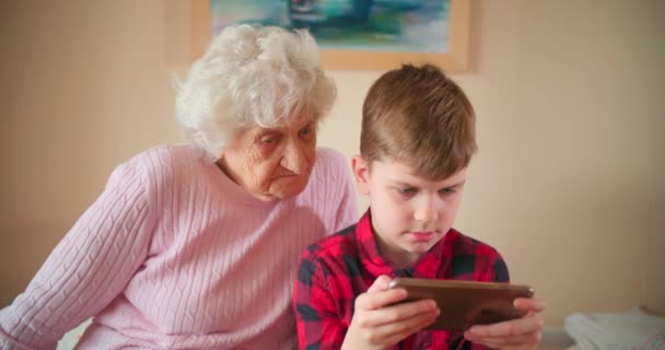 Νεαρό Αγόρι Και Γιαγιά Κοιτάζοντας Την Οθόνη Του Κινητού Τηλεφώνου — Αρχείο Βίντεο