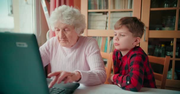 Grand Mère Utilise Ordinateur Portable Pendant Que Jeune Garçon Regarde — Video