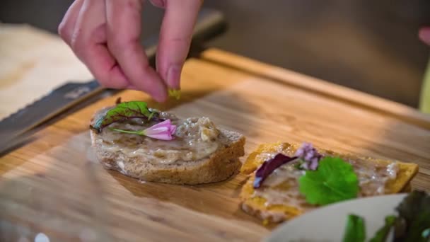 食用の花やハーブと自家製パンの2枚を飾る女性のショットを閉じます — ストック動画