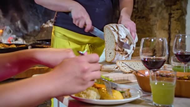 Slow motion of woman eating a traditional Slovenian dish while waitress slices a loaf of bread