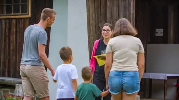 Kobieta Witająca Rodzinę Oferująca Kieliszki Lemoniady Przed Restauracją Wsi — Wideo stockowe