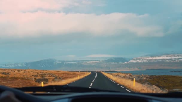 遠くに氷の山があるアイスランドの湖で道路を運転する Slowmo — ストック動画