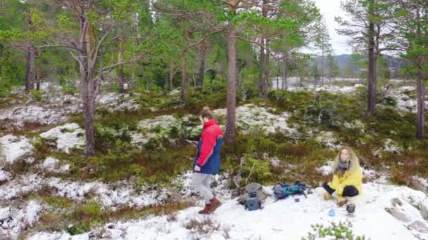 冬は緑の木々に覆われた森の中を雪の上を歩く男がドローンを手でコントロールする — ストック動画