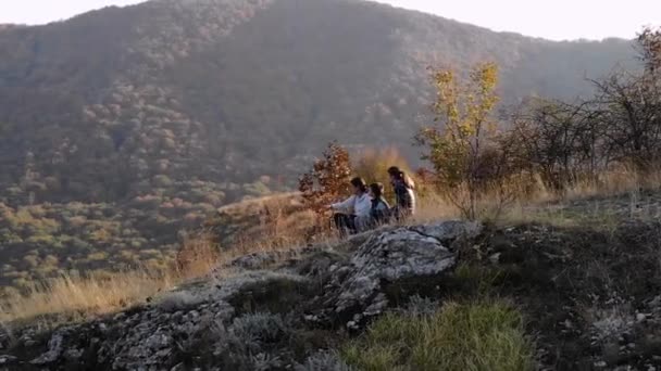 Orbit shot of a mother and kids having a family moment at the top of a mountain at sunset
