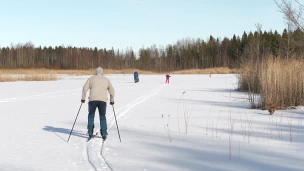 Šťastná rodina si užívá zimní aktivity, severské lyžování na zasněženém zamrzlém jezeře