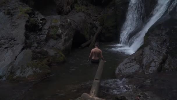 一个年轻人喜欢从瀑布流出来的水流中漫步 — 图库视频影像