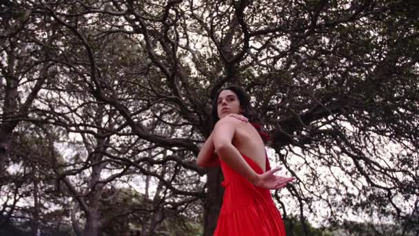 A Woman In Red Ensemble Dancing Gracefully In Front Of The Forest Park. -close up shot