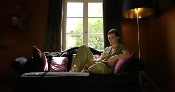 Sofistikovaná žena relaxující v Sofa Swiping na tabletu. Posuvník zastřelen.