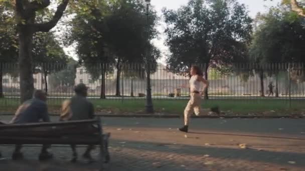 Chica Solitaria Corre Avenida Arbolada Dos Ancianos Banco Miran — Vídeo de stock