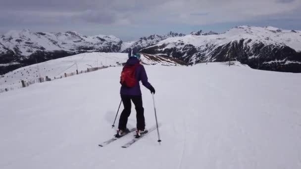 背景に山のある斜面を滑り降りる女性に続くショット — ストック動画
