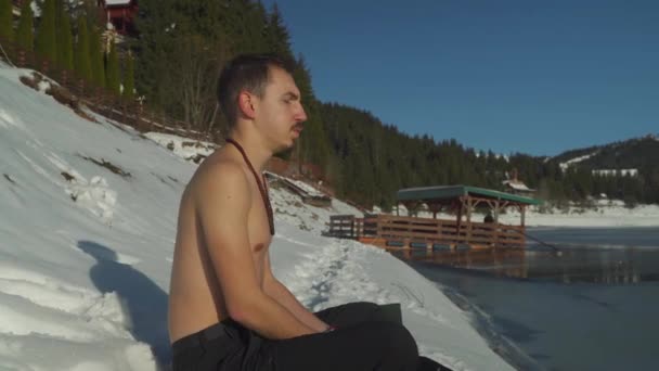 Joven Sin Camisa Sentado Nieve Junto Lago Congelado Montaña Respirando — Vídeos de Stock