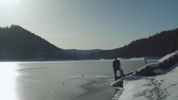 Een Man Staat Aan Kust Van Het Bevroren Meer Transsylvanië — Stockvideo