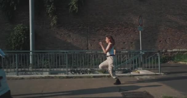 Jonge Vrouw Met Rood Haar Loopt Langs Bakstenen Muur Met — Stockvideo