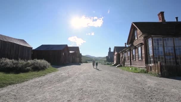 母親と息子は家族旅行者として通りを歩く古い歴史的放棄された鉱山町を訪れる Bodie California — ストック動画