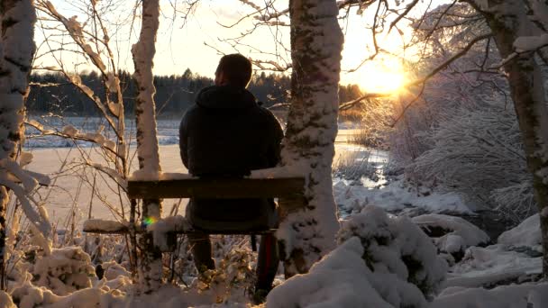 雪の冬の不思議の国でリラックスした孤独な男黄金の夕日 — ストック動画