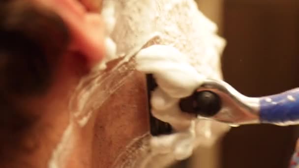 Uzavřený rám ve zpomalení muže holení před zrcadlem s párou ze sprchy