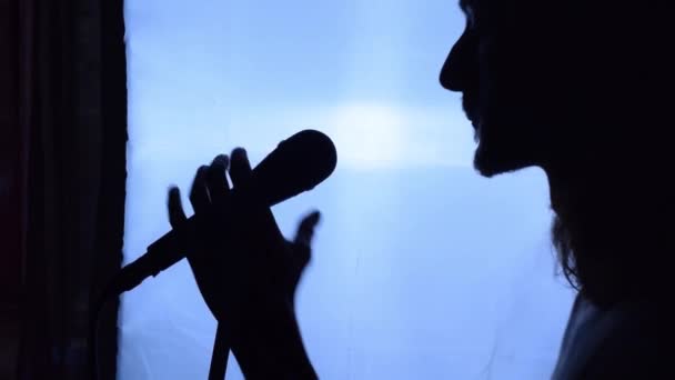 Silueta zpěváka upravujícího mikrofon na stojanu mikrofonu před vystoupením - detailní záběr