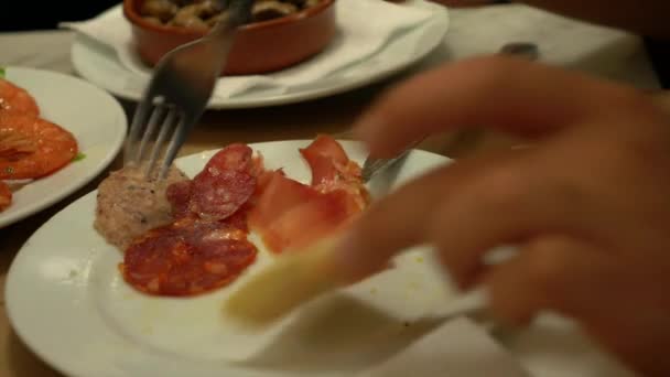 一个孤独的年轻人在餐馆里吃着意大利腊肠和带有面包的开胃酒 — 图库视频影像