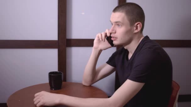 年轻的白种人穿着黑衬衫在咖啡店讲电话 近距离拍摄 — 图库视频影像