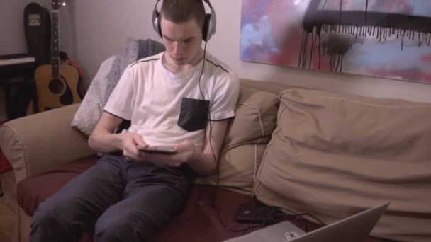 Fiatalember Kanapén Dolgozik Laptopjával Miközben Otthon Zenét Hallgat Közelről — Stock videók