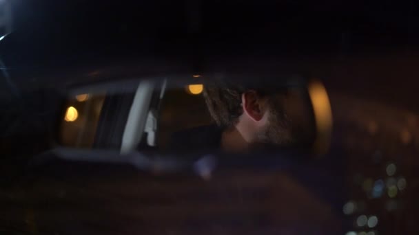 4K záběry muže, jak se dívá do zpětného zrcátka ve svém autě, jak jede v noci.
