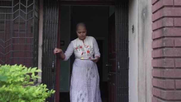 Usmívající se a nadějná pacientka s rakovinou plešatá dívka vyjde z domu s talířem plným barevných prášků po ukončení uzamčení kvůli Covid-19 coronavirus