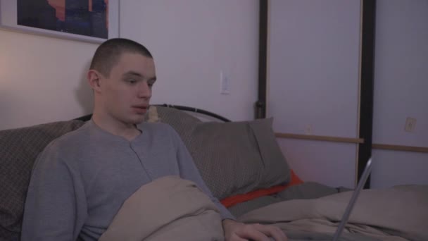 Jovem Sentado Cama Usando Laptop Acenando Conversando Com Seu Colega — Vídeo de Stock