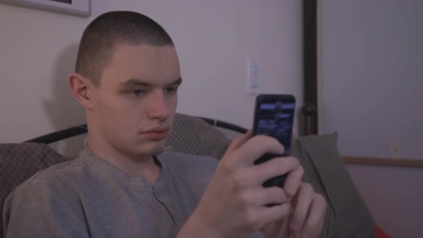 ベッドルームに座っている間にスマートフォンを使用して男 クローズアップショット — ストック動画