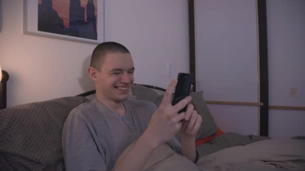 Yatakta Bir Adam Akıllı Telefonuna Bakarken Gülüyor — Stok video