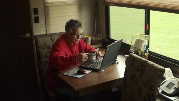 여성은 그라운드에서 안에서 노트북을 가지고 일하다가 커피를 빨아들인다 — 비디오