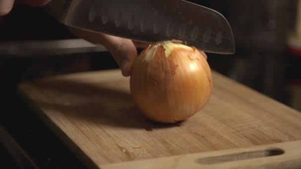 Slicing A Whole White Onion Using A Knife On Wooden Chopping Board. - closeup shot