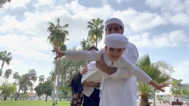 阿拉伯家庭在一起 中东的父亲和他的阿拉伯妻子以及年幼的儿子都喜欢和父母一起玩耍 超级男人的姿态 由他的爸爸抱着 穿着Kandura Abaya — 图库视频影像