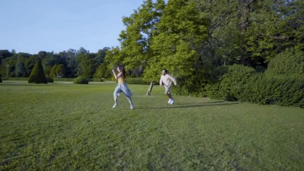 夕暮れ時に公園の後を走る女と男 家族の屋外の楽しみ — ストック動画