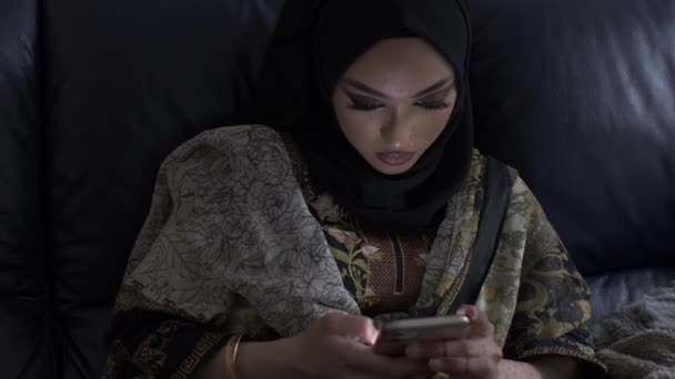 Молодая Мусульманка Сидит Помещении Любуясь Смартфоном — стоковое видео