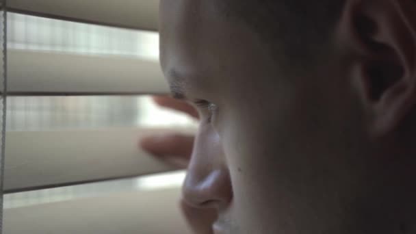 Unge Man Tittar Genom Fönstret Persienner Från Sängen Rummet Närbild — Stockvideo