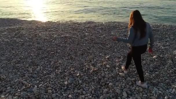 海と太陽の方へ岩のビーチを歩く白人女性 カフラビダ レバノン 空中回転 — ストック動画
