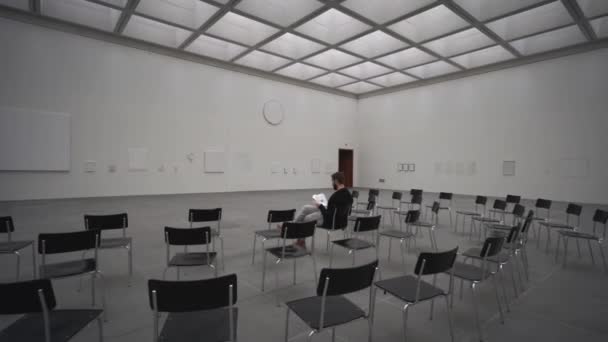 Giovane Solitario Siede Una Delle Tante Sedie Una Sala Museo — Video Stock