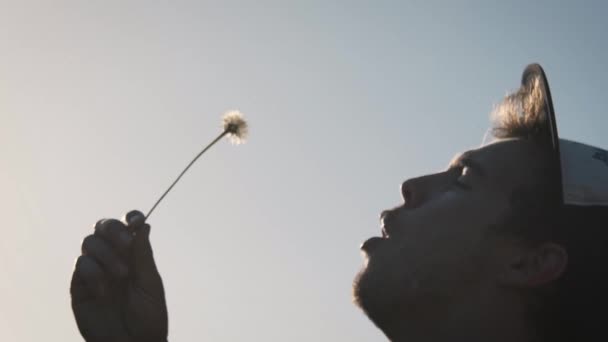 Adult Male Wearing Hat Blowing Dandelion Sunset Slow Motion Dreamy — Stock Video
