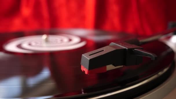 Djターンテーブルレッドベルベットの背景に12ブラックビニールレコードにスタイラスアームと針が下がりました レトロLpプレート 閉めろ 人気のある音楽機器 ディスコ パンク グランジ ポップ60年代 70年代 80年代 — ストック動画