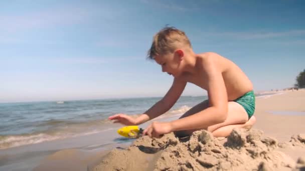 Молодий Хлопець Купальнику Грає Пляжі Копає Стежку Пісок Лопатою — стокове відео