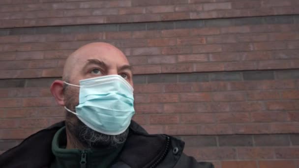Férfi biztonsági őr visel védő koronavírus orvosi PPE maszk jobb pan ellen téglafal