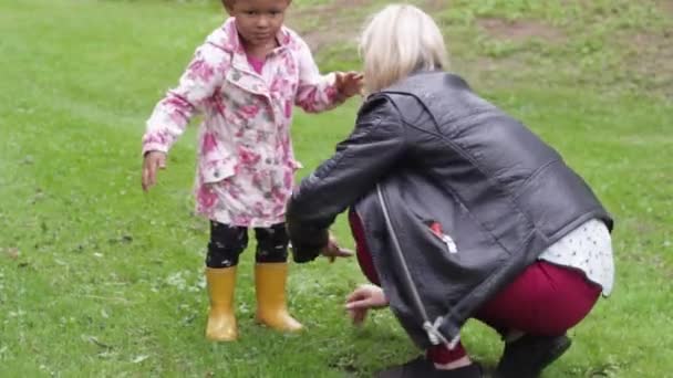 ヨーロッパの白い母親が彼女をオフに汚れをきれいにしながら 公園で活気のある小さなアフリカの子供は左を指す再生したい ハンドヘルド — ストック動画